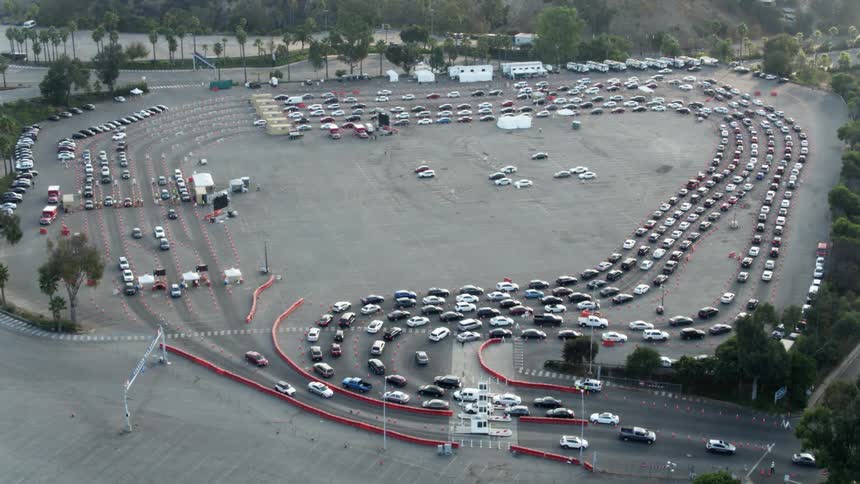 Cars wait in line to pass through temp buildings then slowly leave