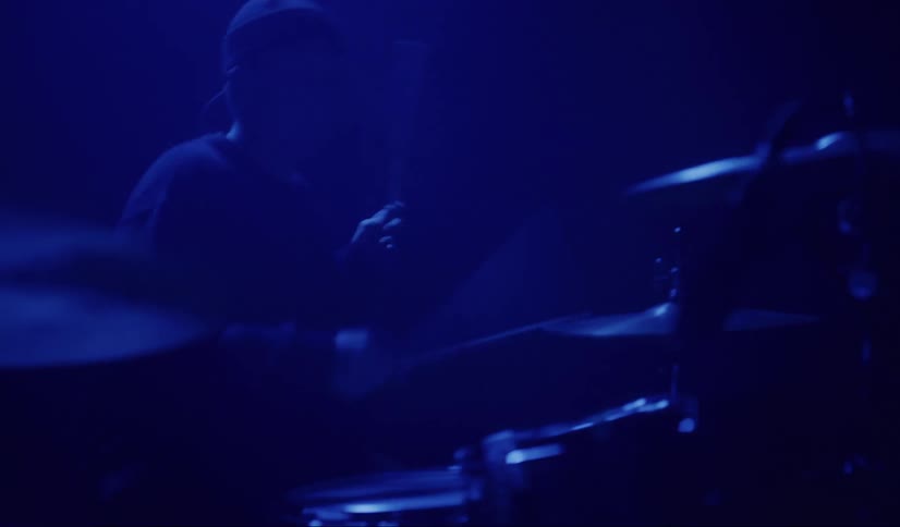 A man rocks out and head bangs while playing the drums
