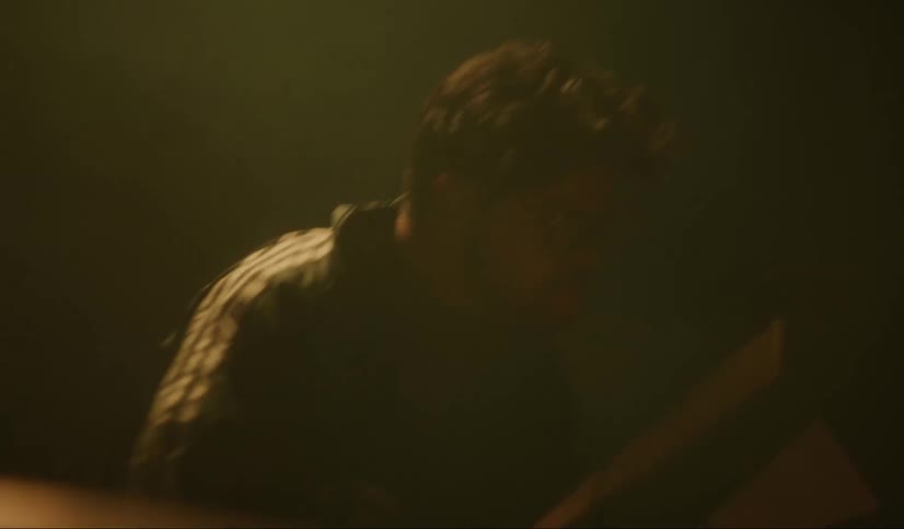 A man plays the drums as stage light reflects on his drum set
