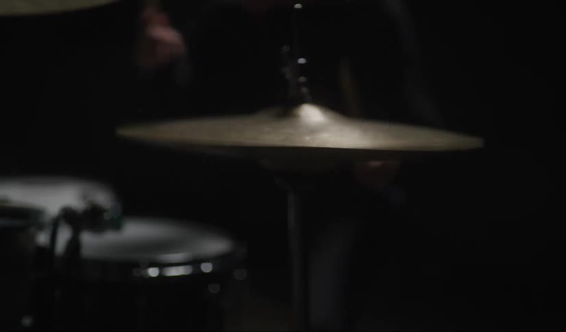 Man wearing a black toque plays the drums and cymbals with drumsticks