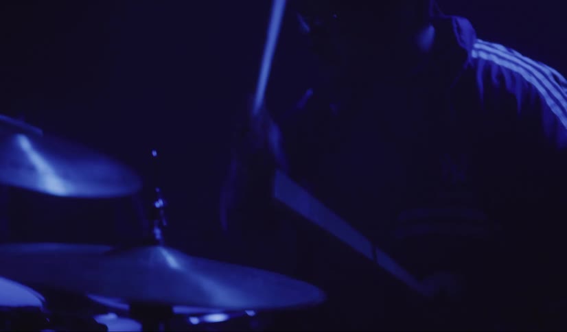 Drummer plays drums on dark stage