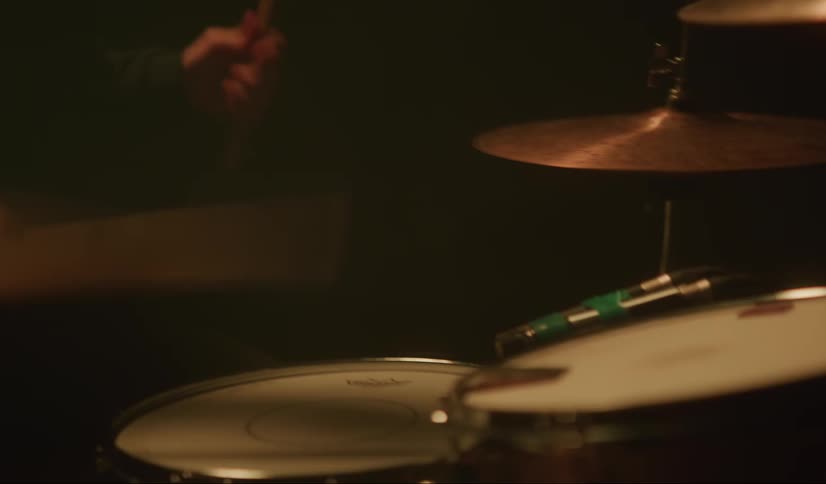 A man plays the drums in a dark room