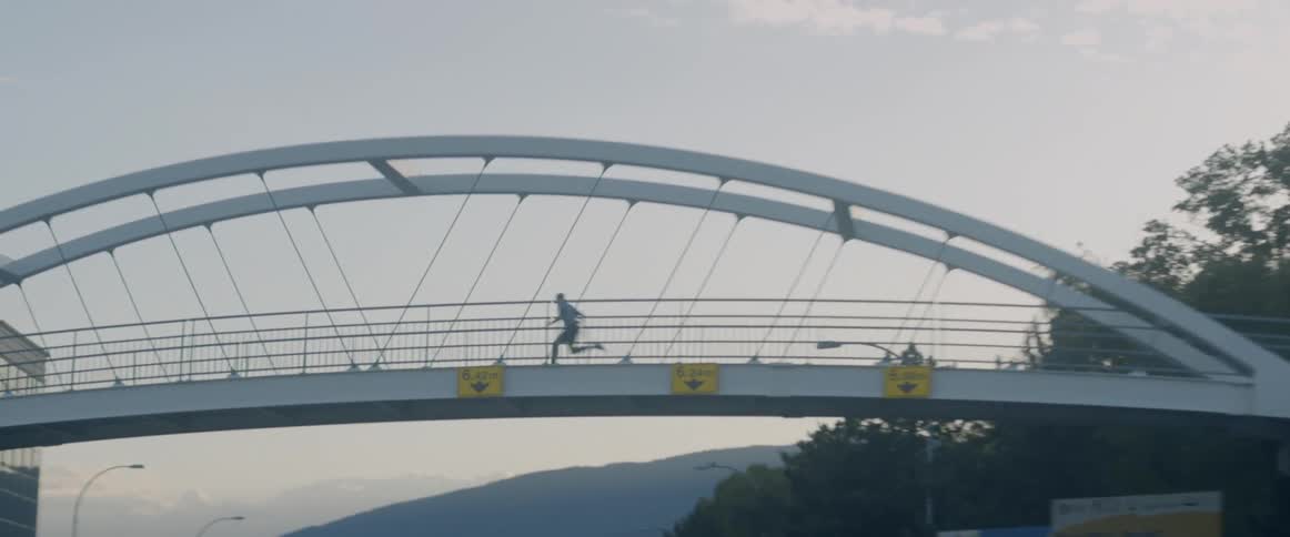 Person runs over a bridge with cars driving underneath it