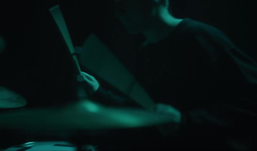 Musician plays drum set on dark stage