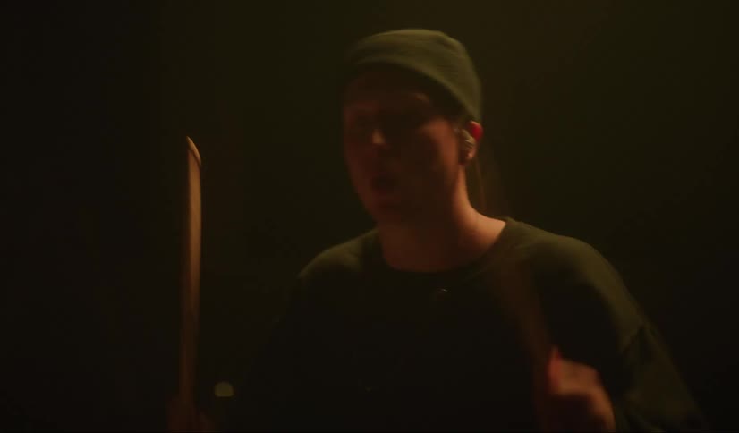 A drummer plays as stage lights glow blue