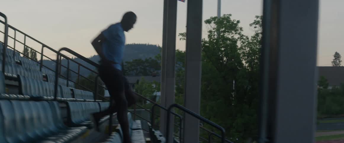 Man runs down some stairs in outdoor bleachers