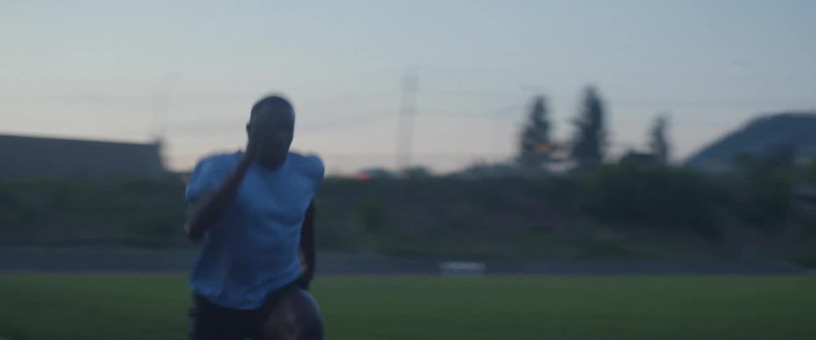 Man in a short sleeved shirt sprints down a racetrack