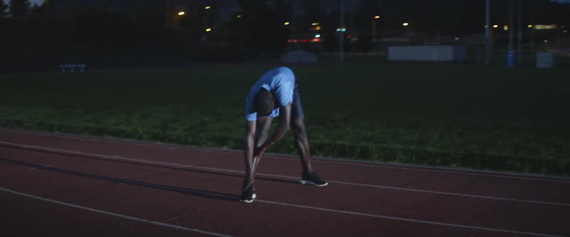 A man stretches outside at night