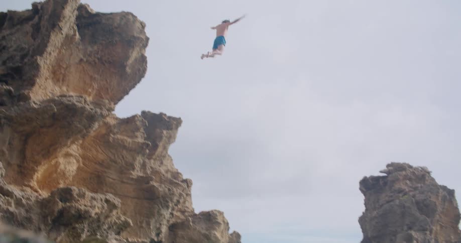 A man diving off of a cliff into the ocean