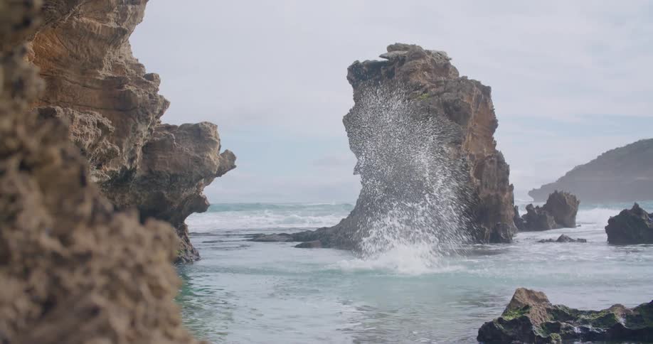 A man jumps off a cliff hitting the water feet first