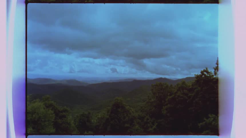A range of trees and hills sits under a cloudy sky