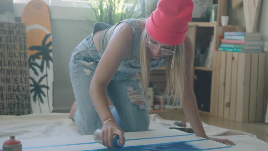 A woman painting on canvas in a room