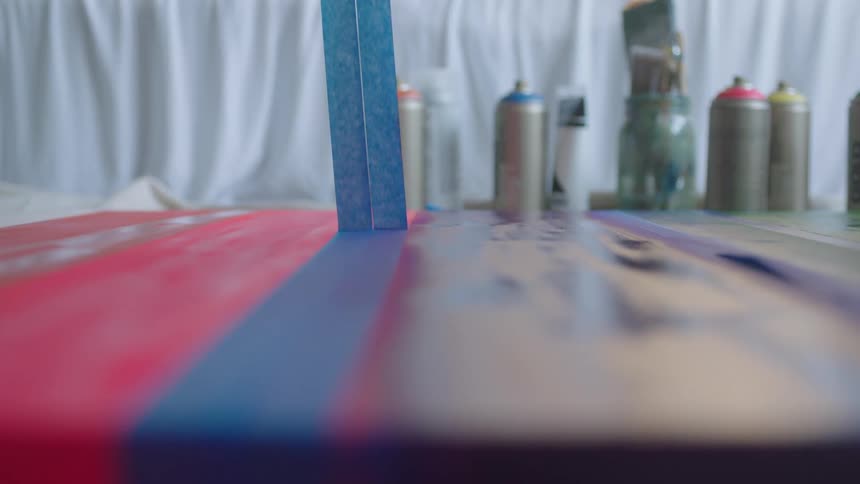 A painter peeling up tape on a painting