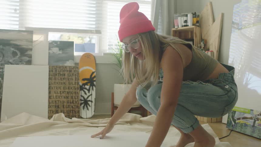 A woman lays a blank canvas on the tarp