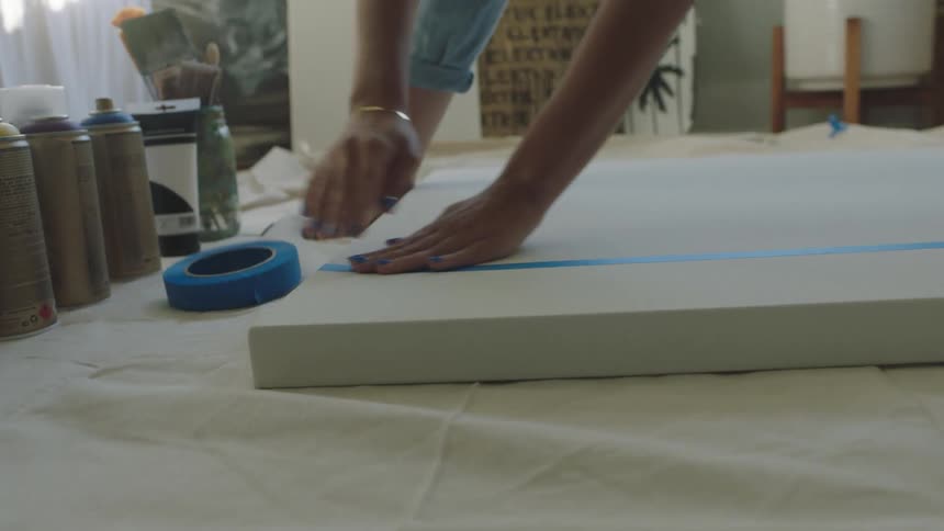 A woman putting tape on a canvas to paint