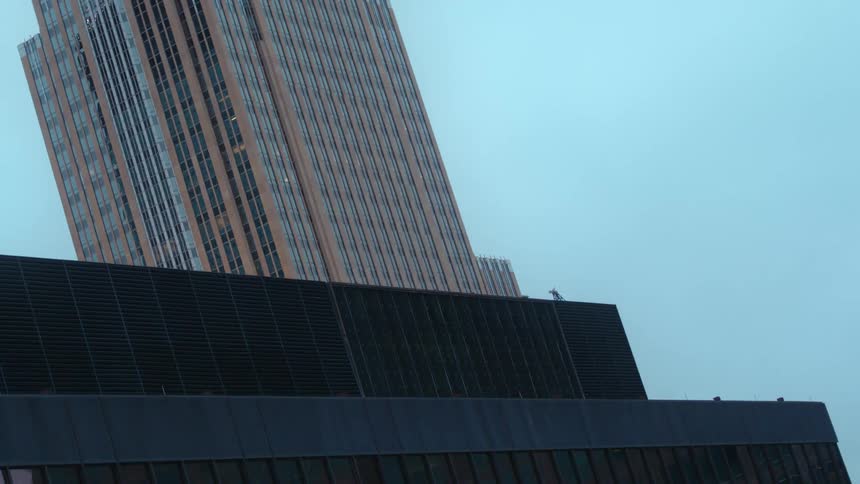 Construction crane sits next to a skyscraper under a blue sky