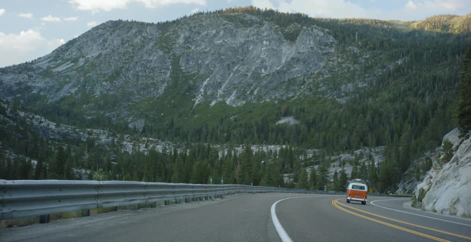 A volkswagen bus travels on a mountain road