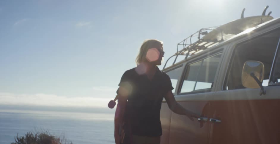 A man stands outside of an orange van
