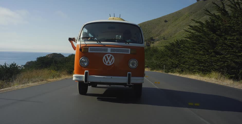 Van driving on a road next to a beach