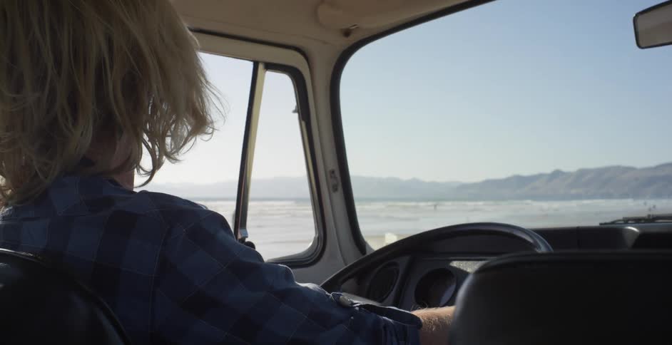 A man looks out the window as he drives on the beach