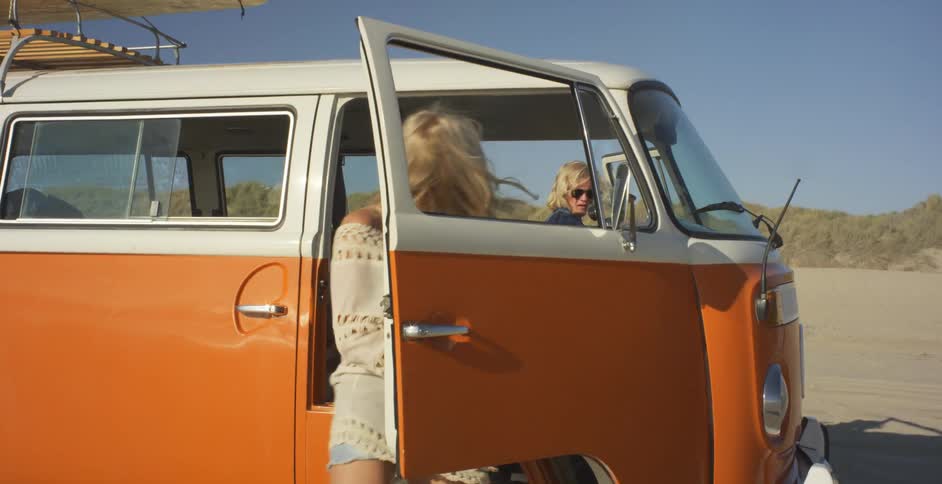 A man and woman get out of a van on a sunny day