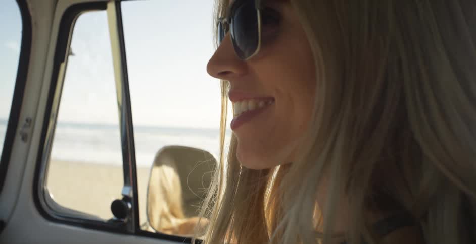 Blond woman sits in a vehicle as she smiles