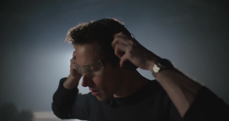 A man puts on safety glasses and hearing protection before using a power sander on a wooden table