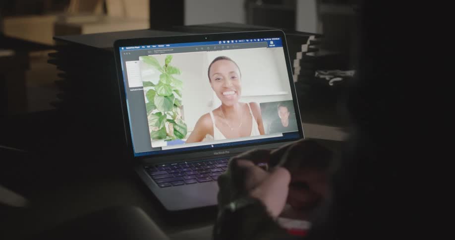 A man and woman wave at each other during a video call on a laptop