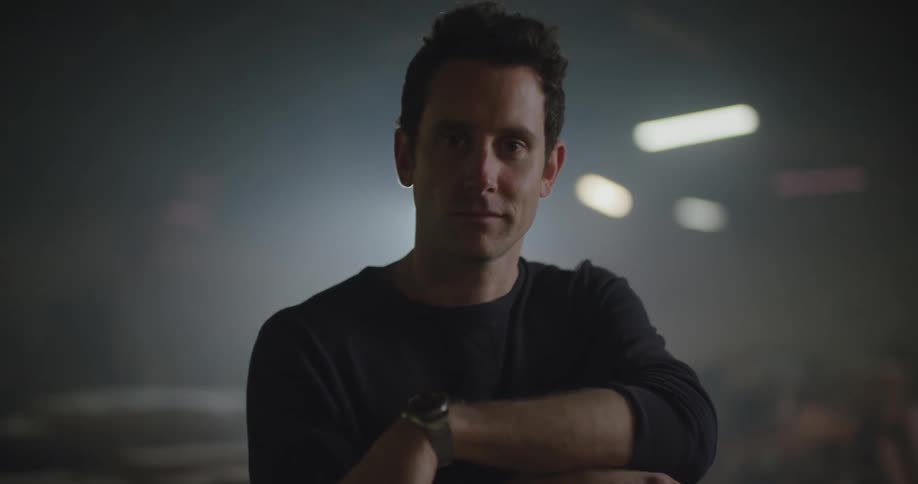 Young man standing inside a dimly lit warehouse looking at the camera
