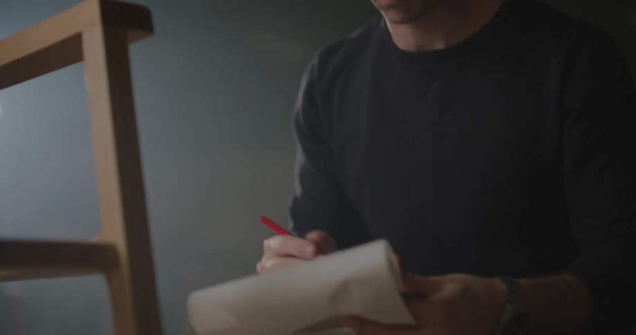 A man is standing indoors and drawing
