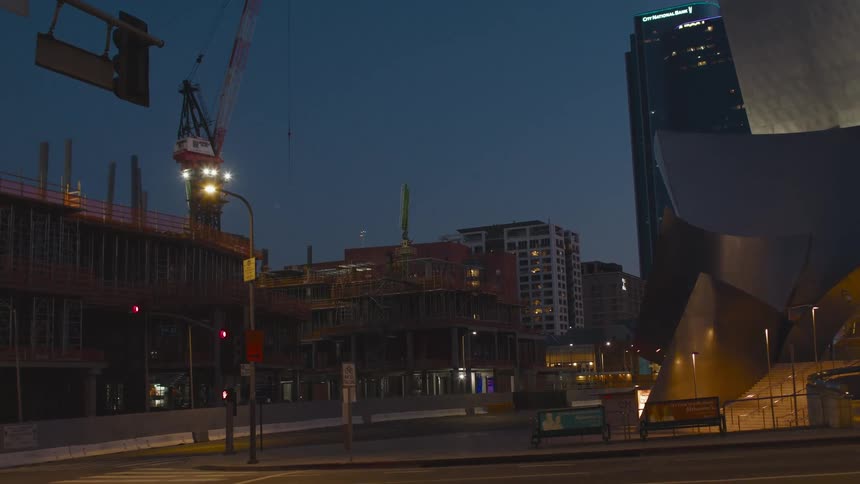 Construction cranes in the city downtown at evening