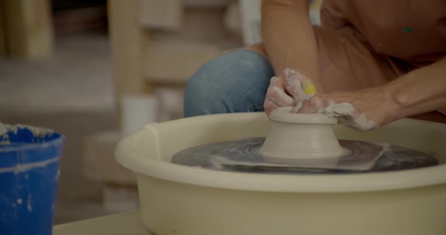 A person molding clay on a spinning wheel
