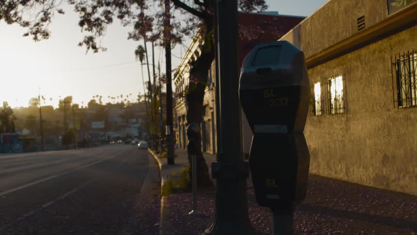 Cars travel down the street as parking meters line the sidewalk