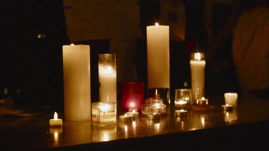 Assortment of candles burning over a table at night