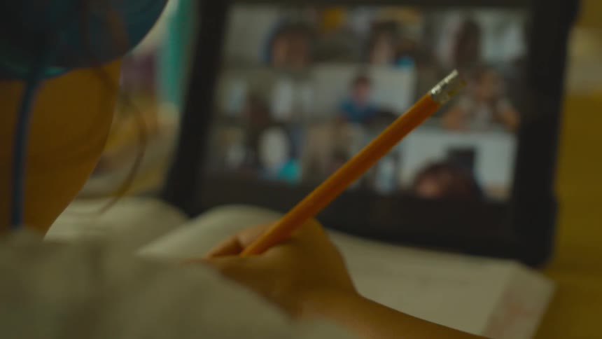 A young girl participates in a virtual class while using a computer tablet
