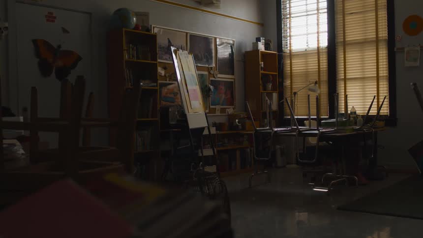 Furniture inside a dimly lit classroom inside a closed school