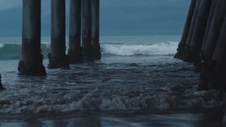 Waves rolling in under a pier