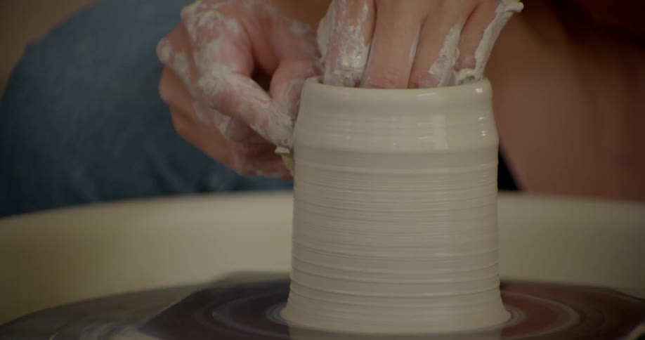 A person is spinning clay on a wheel