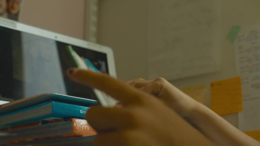 A child is reading a textbook in front of a laptop
