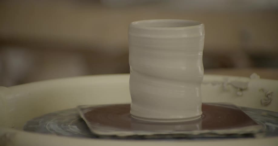 A pottery wheel spins with a clay sculpture rotating