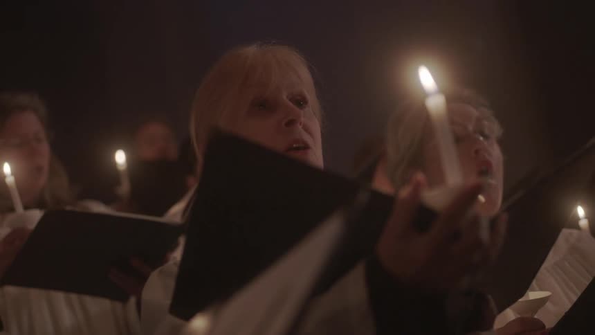 A church choir performs while holding candles
