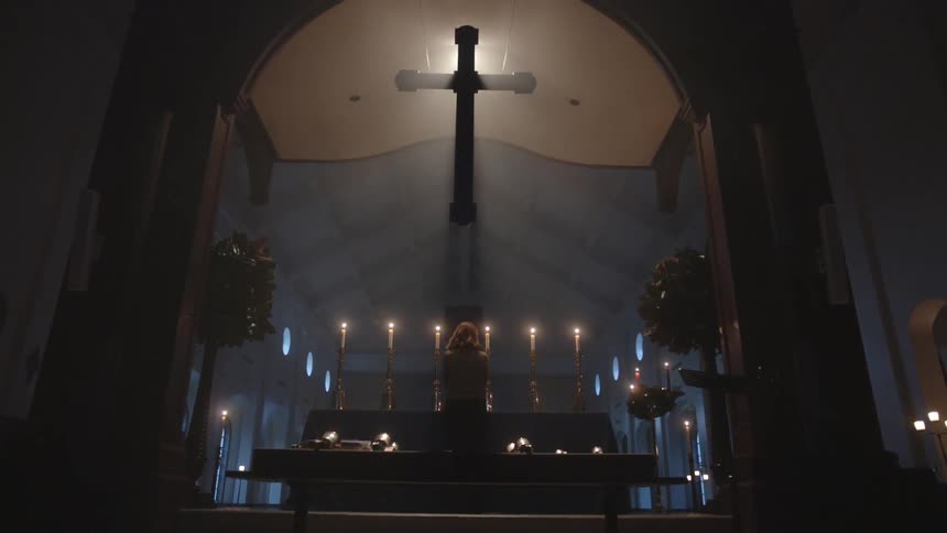 A person is standing in a church with a cross behind