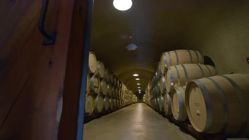Wooden doors lead to two rows of stacked large wooden kegs separated by center hallway