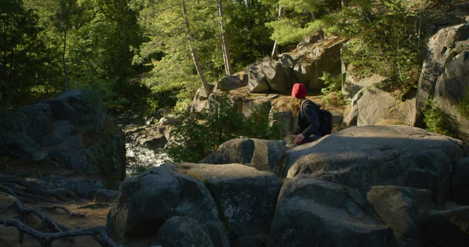 A woman is hiking in a wooded area near a river