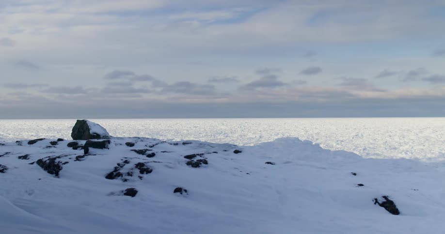 Snow covered surface stretches to horizon sitting partly in shadow and partly in sunlight