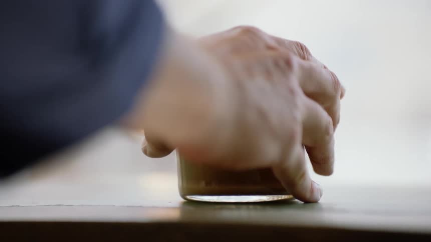 Mans hand puts coffee glass on the table