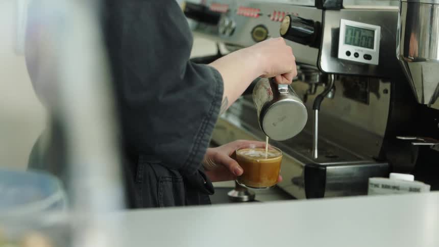 A woman is making coffee at a shop