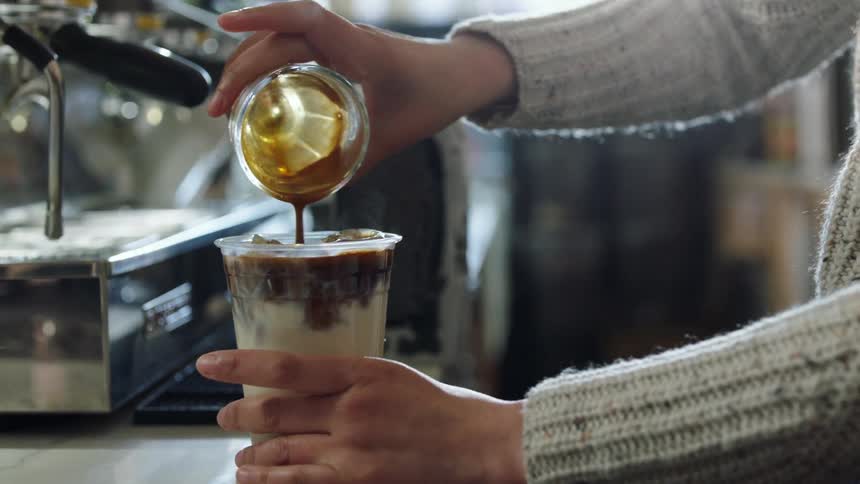 A woman prepares an espresso in a coffee shop during the day