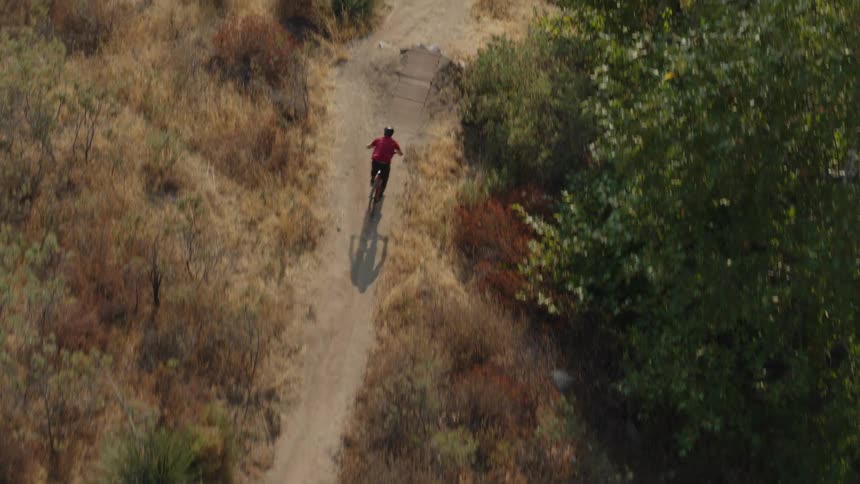 Aerial view of a cyclist riding a bicycle on a dirt trail on the mountains
