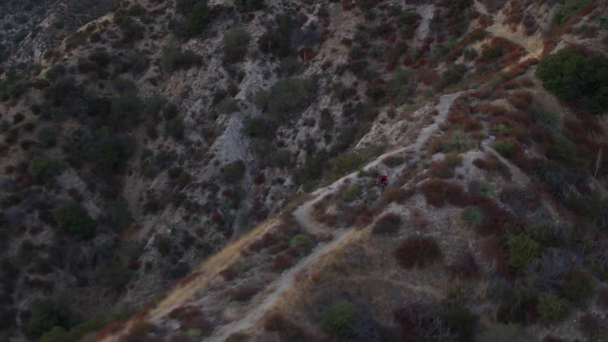 A cyclist is riding a bicycle on a trail across the top of a mountain